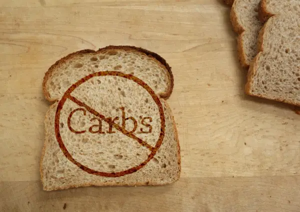 Kromka chleba z przekreślonym napisem "Carbs". Idealne dla osób szukających produktów bez węglowodanów, tabela z nimi może być pomocna.
