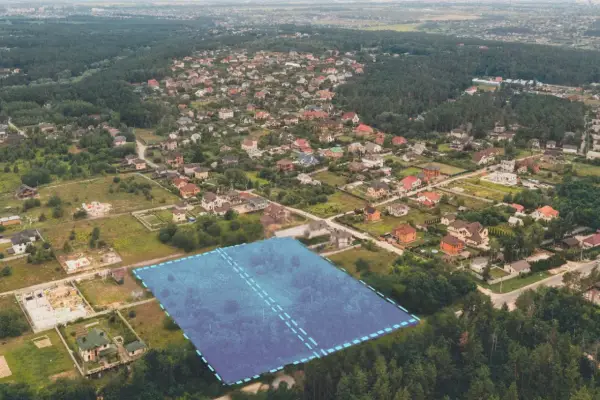 Działki bez planu ogólnego gminy będą niesprzedawalne od lipca 2026. Aerial view of suburban housing development with a highlighted plot of land.
