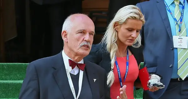 Janusz Korwin-Mikke z wąsem i w muszce, obok niego kobieta w czerwonej sukience. Może to jego dzieci?