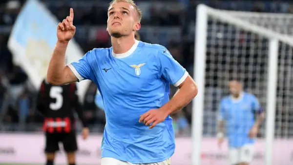 Piłkarz Lazio w błękitnej koszulce z uniesionym palcem, radośnie świętuje bramkę w meczu z A.C. Milan.