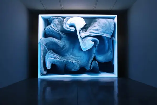 Une oeuvre d'art numérique captivante, aux formes bleutées et texturées, évoquant un nuage ou une vague figée dans un cube lumineux.