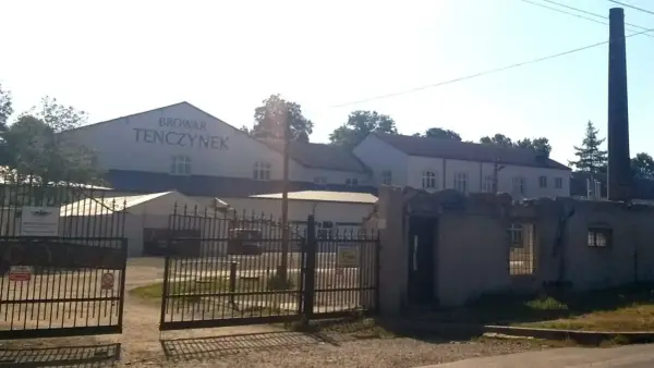 Brama wjazdowa do Browaru Tenczynek. W tle budynki browaru i wysoki komin.