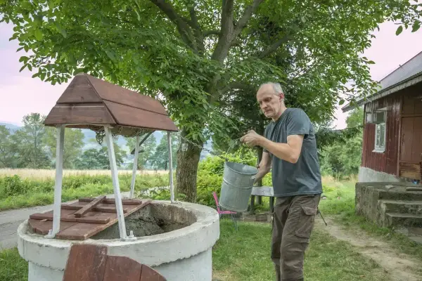 Mężczyzna czerpie wodę z **studni głębinowej**. Czy posiada **pozwolenie** na jej budowę?