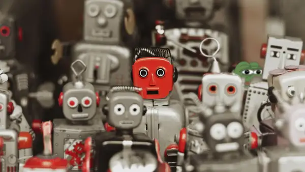 Kolekcja robotów zabawek, w tym jeden czerwony z przerażonym wyrazem twarzy, przypomina teorię martwego internetu.