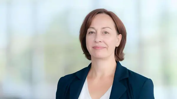 Agata Witkowska, aktorka, w granatowej marynarce i białej bluzce, uśmiecha się lekko.