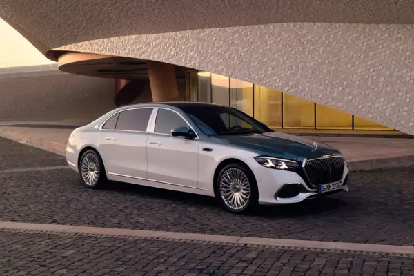 Elegancki Maybach S580 w dwukolorowym malowaniu, zaparkowany przed nowoczesnym budynkiem o geometrycznej fasadzie.