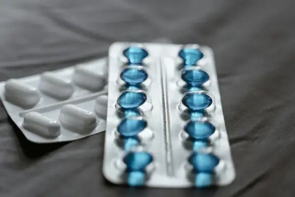 Dwa blistry leków: jeden z białymi kapsułkami, drugi z niebieskimi, prawdopodobnie pregabalin zentiva.