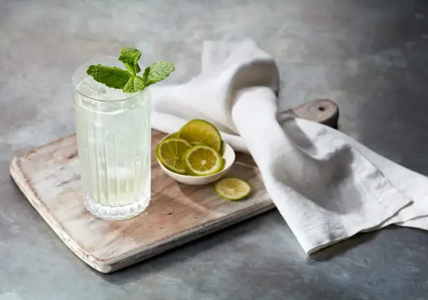 Orzeźwiający mojito z ginem, udekorowany miętą i podany z plasterkami limonki na drewnianej desce.