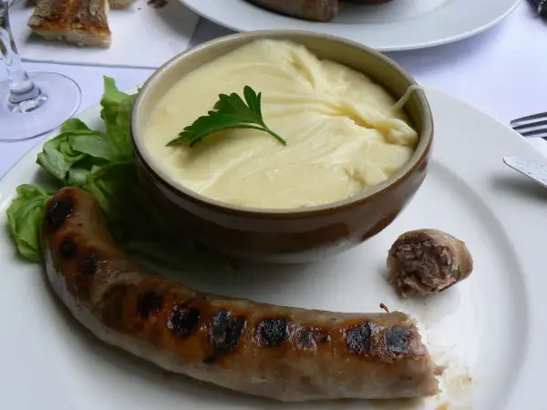 Saucisse grillée et purée onctueuse, un plat traditionnel auvergnat réconfortant.