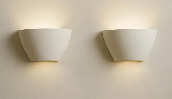 Dos elegantes flexos de pared blancos emiten una luz cálida y difusa, creando un ambiente acogedor en la estancia.