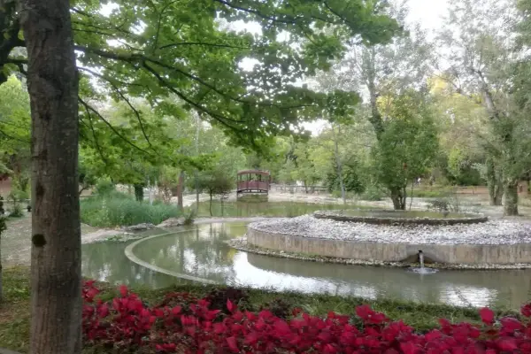 Un laghetto con un ponticello in legno e aiuole fiorite nel Parco della Resistenza a Riccione.