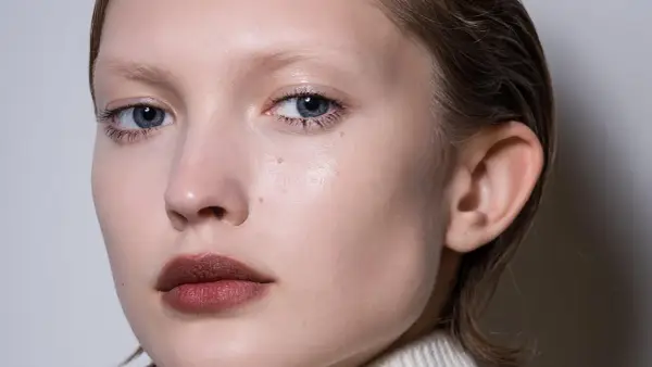 Primer plano de un rostro cuadrado con ojos azules y labios oscuros.