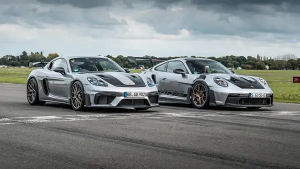 Zwei silberne Porsche GT4 und GT4 RS stehen nebeneinander auf einer Rennstrecke.