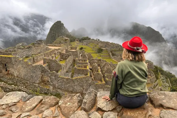 Kobieta w czerwonym kapeluszu podziwia Machu Picchu. Czy w Peru jest bezpiecznie? Tak, to bezpieczna podróż do serca Inków.