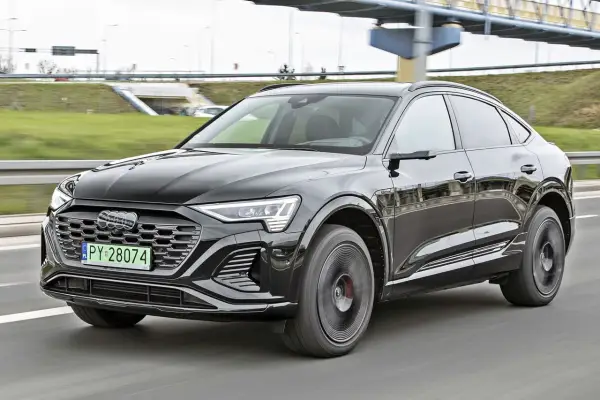 Czarny Audi Q8 e-tron sunie po drodze. Zastanawiasz się nad audi q8 cena? Ten luksusowy SUV coupe robi wrażenie.