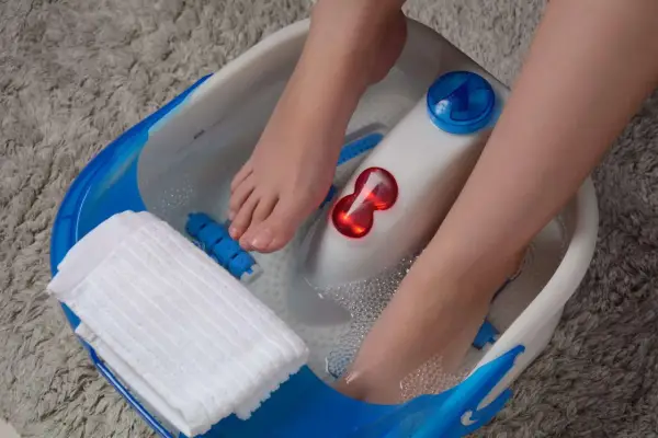 Pieds dans un bain à bulles, profitant d'un moment de détente pour la beauté des pieds. Une serviette blanche est à portée de main.