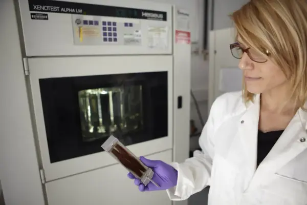 Científica con guantes morados examina una muestra de cabello en un laboratorio. Se investiga de que esta hecho el pelo para mejorar productos.