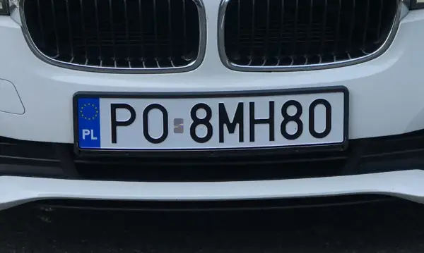 Biały samochód z polską tablicą rejestracyjną PO 8MH80.