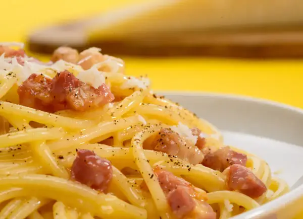Pyszne spaghetti carbonara z kawałkami boczku i posypką. Szukasz, czym zastąpić parmezan?