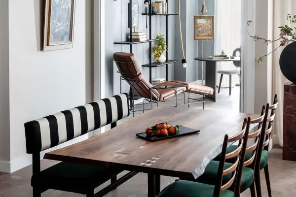 A large, live-edge wooden table with inlaid details, showcasing its impressive table dimension, is set with a tray of tangerines.
