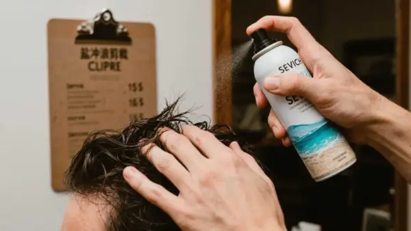 Un hombre aplica spray sal marina pelo para un look playero.