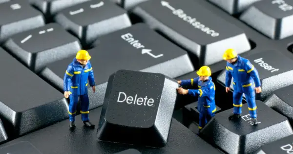 Figurki robotników w niebieskich kombinezonach próbują usunąć klawisz "Delete" z klawiatury. Działają jak incogni, usuwając niechciane dane.