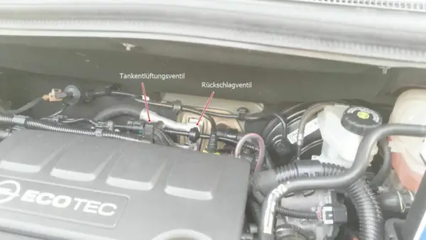 Motorraum eines Opel mit markiertem Tankentlüftungsventil und Rückschlagventil. Der Fehlercode p0171 kann hier relevant sein.