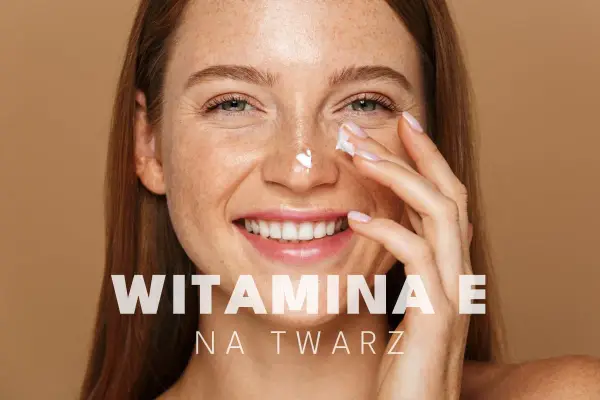 Uśmiechnięta kobieta z piegami aplikuje krem pod oczy. Witamina E na twarz dla promiennej cery.