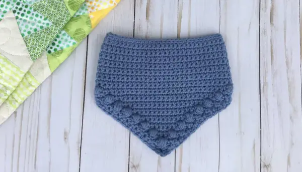 Babero azul tejido a crochet con detalle de pompones. Patrones baberos crochet instrucciones para crear esta linda prenda.