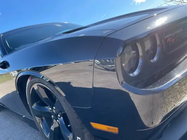 Svart Dodge Challenger med en glans som en ängel, tack vare angelwax. Solen reflekteras i den blanka lacken.