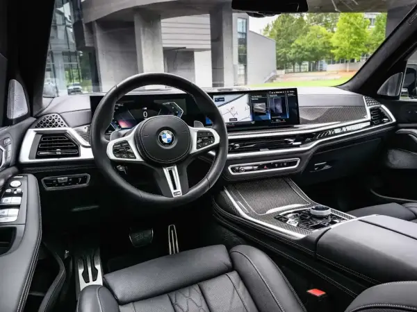 Wnętrze BMW x7: skórzana tapicerka, nowoczesny kokpit z dwoma ekranami i sportowa kierownica.