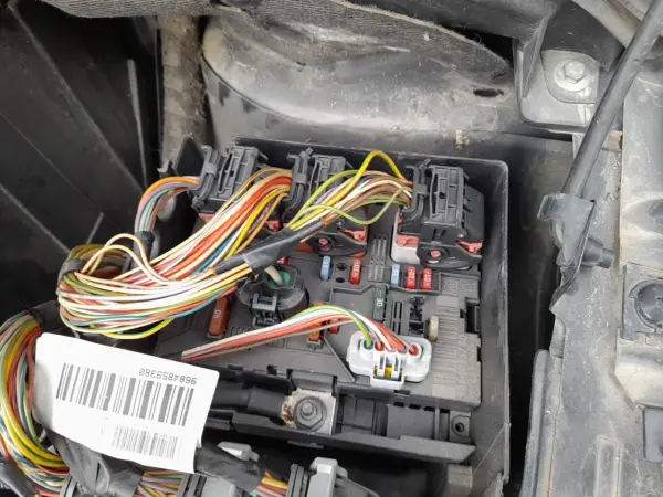 Widok na skrzynkę z bezpiecznikami i wiązką przewodów w Peugeot 307. Widać kolorowe kable i oznaczenia bezpieczników.