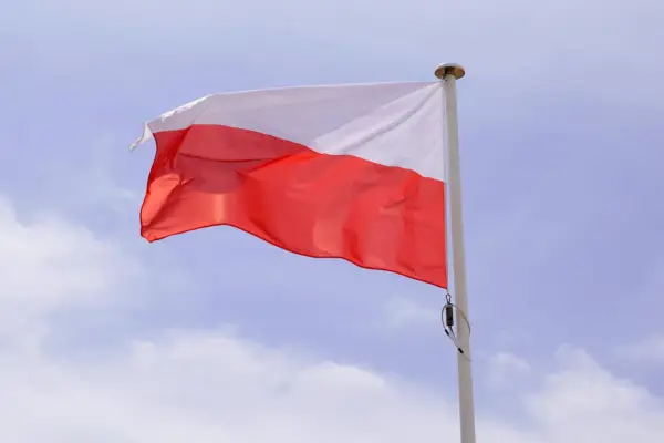 Biało-czerwona flaga powiewa na maszcie. Duma i symbole narodowe Polski w błękitnym niebie.
