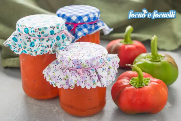 Barattoli di crema di peperoni fatti in casa, con peperoni freschi sullo sfondo.