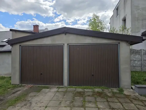 Dwa brązowe, segmentowe bramy garażowe w murowanym garażu. Zastanawiasz się, ile kosztuje wynajęcie garażu murowanego?