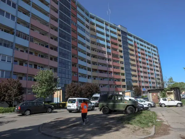 Długi, wielopiętrowy blok mieszkalny, prawdopodobnie najdłuższy blok w Polsce, z kolorowymi balkonami i oknami, na tle błękitnego nieba.