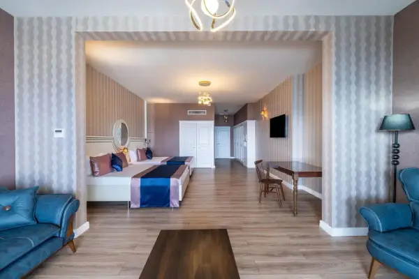 Przytulny pokój w Orange County Resort Alanya z dwoma łóżkami, niebieską sofą i stołem.