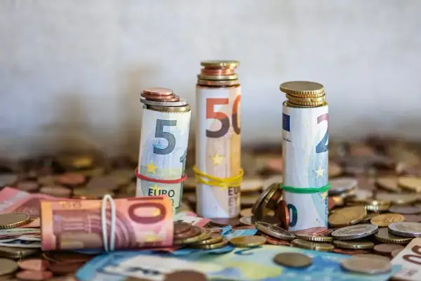 Zwijane banknoty euro i monety, symbolizujące kwotę darowizny wolną od podatku, tworzą stosy na tle innych monet.