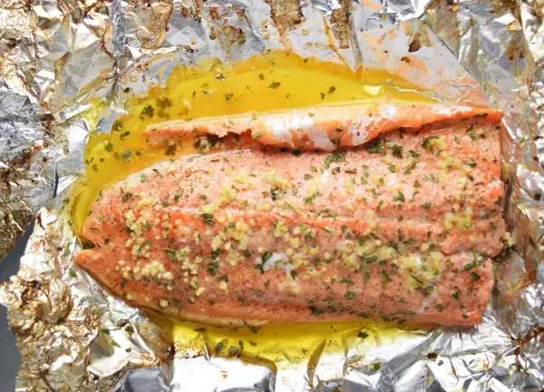Filet de truite cuit en papillote, assaisonné d'ail et d'herbes, baignant dans un jus doré. Une recette simple et savoureuse.