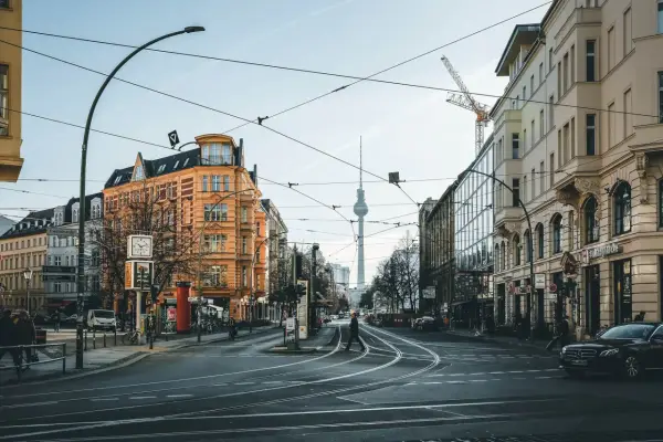Skrzyżowanie w Berlinie z widoczną wieżą telewizyjną. Czy Berlin jest bezpieczny? Miasto tętni życiem, a ludzie swobodnie poruszają się po ulicach.