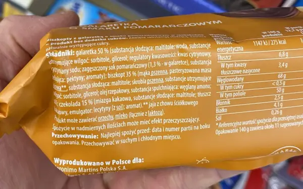 Pomarańczowe delicje kcal: biszkopt z galaretką i czekoladą. Na opakowaniu podano składniki i wartości odżywcze, w tym 275 kcal na 100g.