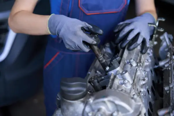 Mecánico con guantes trabajando en un motor, mostrando componentes como inyectores y partes del cigüeñal.
