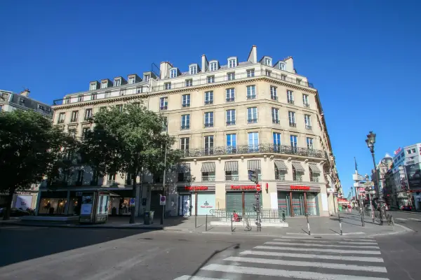 Elegancka kamienica przy rue de Rivoli w Paryżu, z markizami nad oknami i sklepem Foot Locker na parterze.