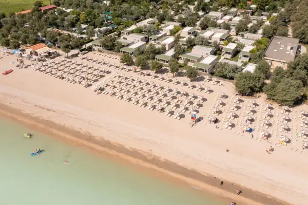 Domenica di sole sulla spiaggia di Rivazzurra, con ombrelloni, lettini e bagnanti che si godono il mare.