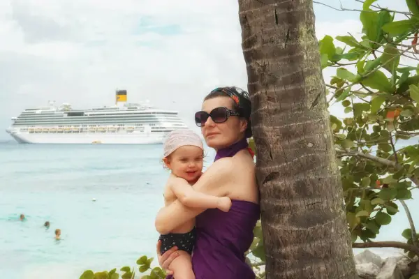 Mamma e bimbo abbracciati vicino a una palma, con una nave da crociera all'orizzonte. Una splendida posizione costa pacifica.