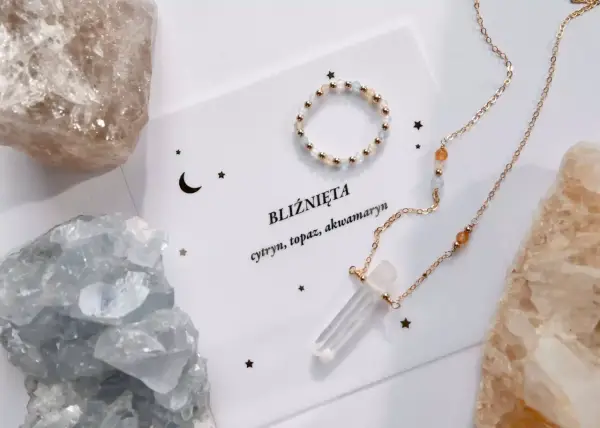 Delikatna biżuteria z kamieniami, w tym akwamaryn, otoczona surowymi kryształami.