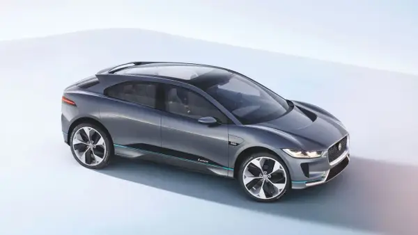 Elegancki, szary Jaguar I-PACE, niczym czarny jaguar gotowy do skoku, prezentuje swoją aerodynamiczną sylwetkę na jasnym tle.