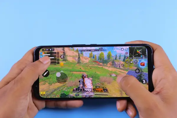 Ręce trzymają smartfon, na którym widać dynamiczną rozgrywkę z jednej z najlepszych gier android. Akcja toczy się w malowniczej, górskiej scenerii.