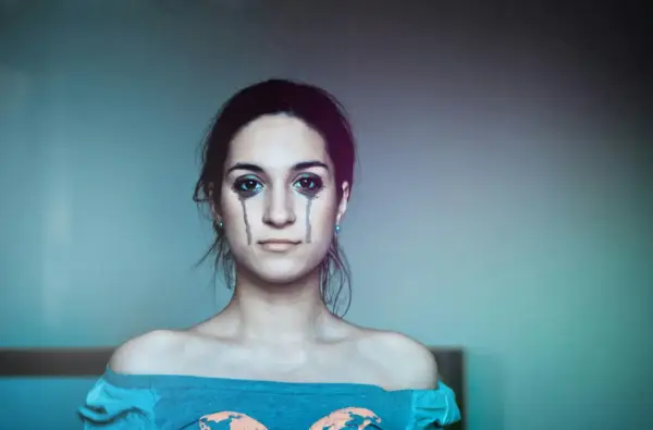 Ragazza con trucco che simula lacrime, espressione di labilità emotiva, alla ricerca di cura e comprensione.