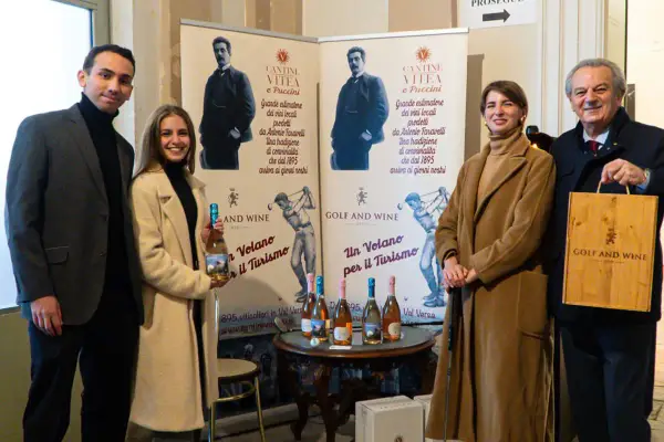 Antonio Faravelli, un nome legato alla tradizione vinicola. Quattro persone sorridono davanti a banner che celebrano la storia di Cantine Vitea e Puccini.